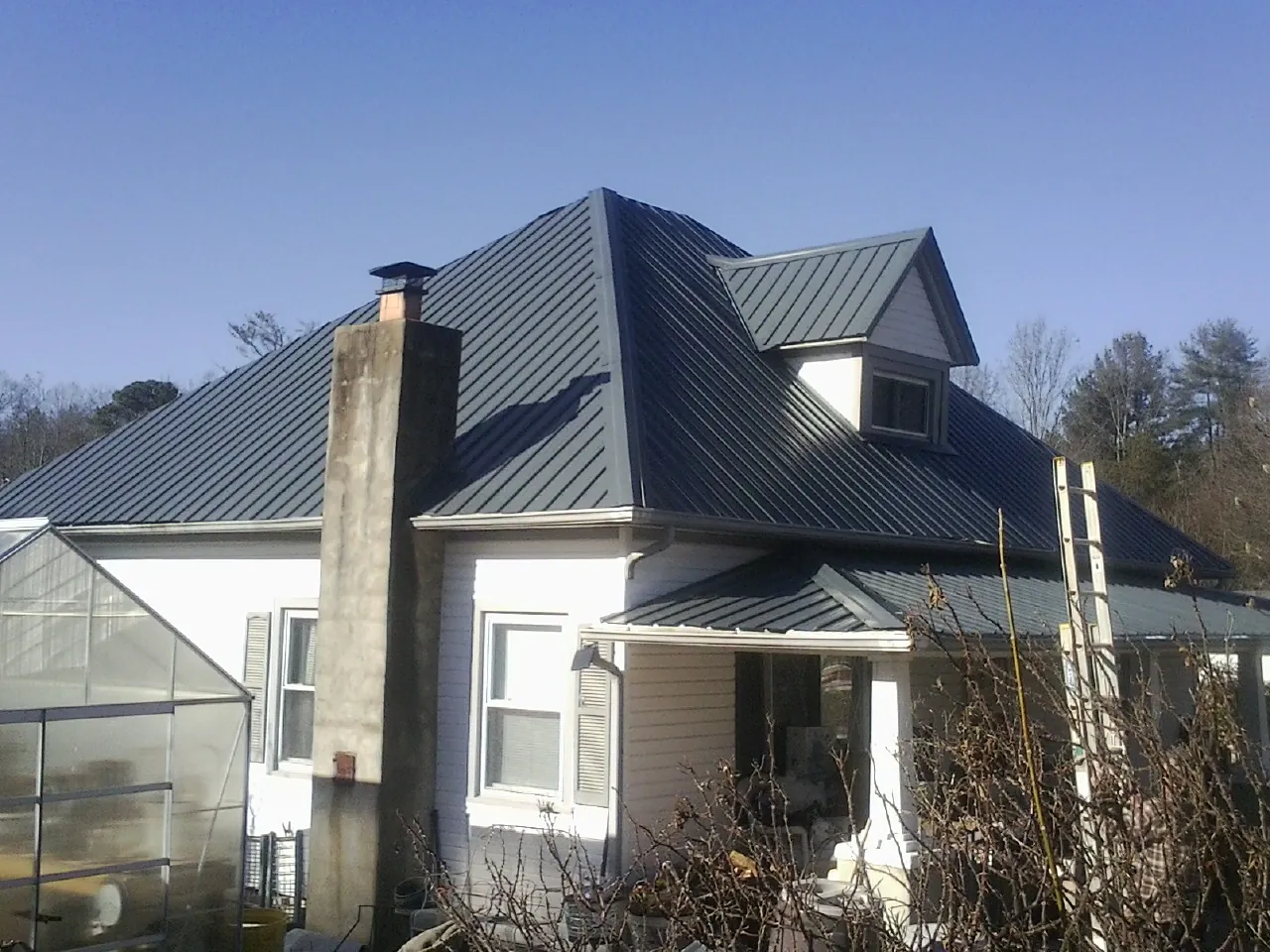 Dark blue standing seam metal roof on a white farmhouse with dormer — Slate & Tile Roof Repair by Roofing Brothers in Copeland