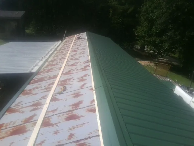 Old rusted panels beside newly installed green metal roofing — Wind Damage Roof Repair by Roofing Brothers in Copeland