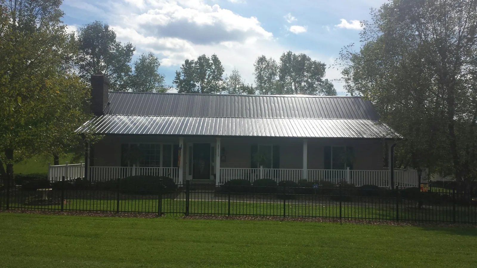 Gray metal roof on a brick ranch with a full width front porch — Gutter Guard Installation work by our crew in Copeland
