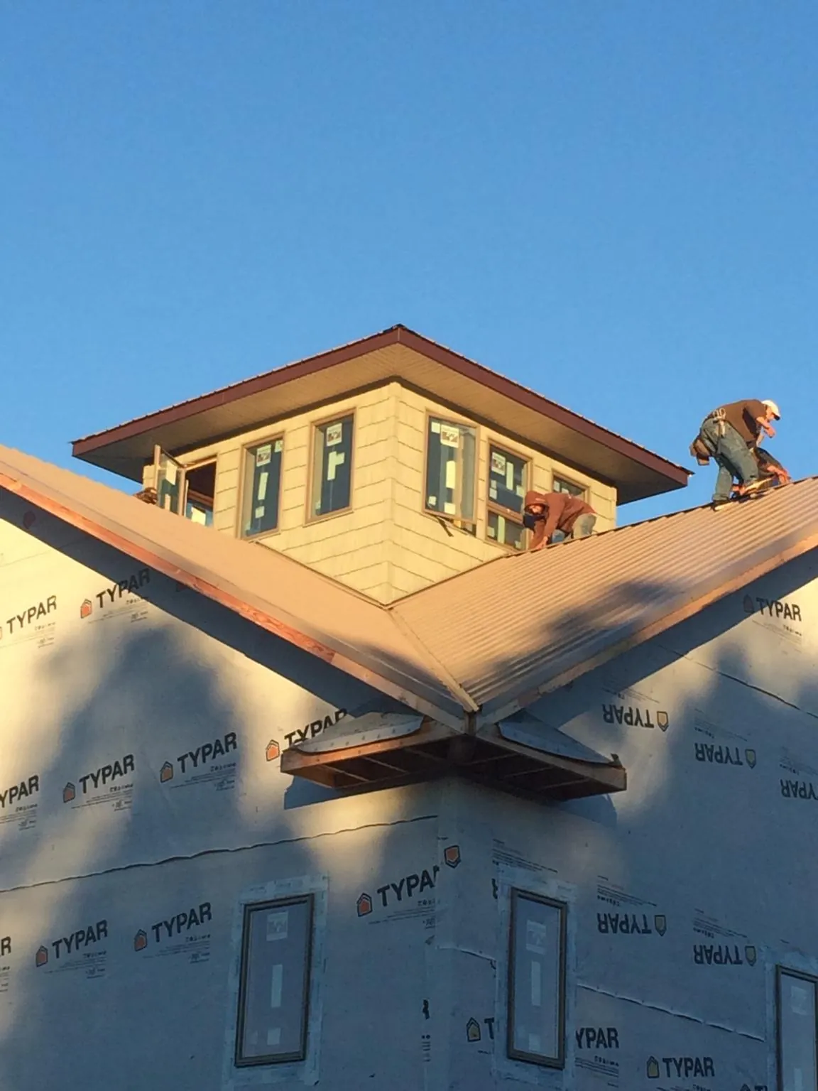 Roofers working around a rooftop cupola on a new metal roof at sunset — Roof Waterproofing in Copeland by Roofing Brothers